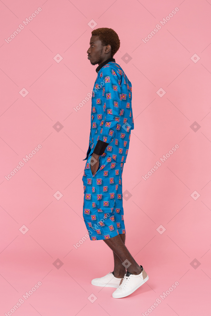 ピンクの背景に立っている青いパジャマで黒人男性