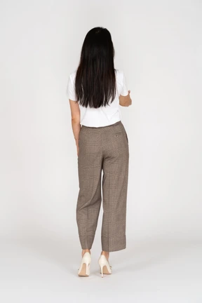 Vista posterior de un saludo señorita en calzones y camiseta extendiendo su mano