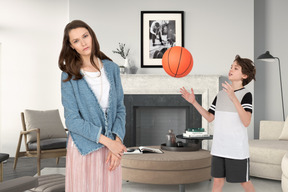 Woman standing next to a boy playing basketball in a living room
