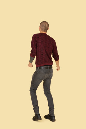 Back view of a dancing young man dressed in red pullover