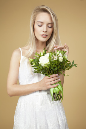 Schöne junge braut, die blumenstrauß von weißen blumen hält