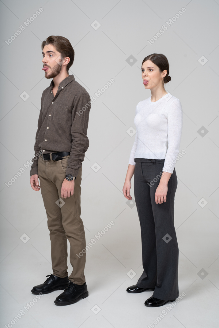 一对年轻夫妇在显示舌头的办公室服装的四分之三视图