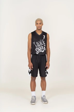 Front view of a smirking young male basketball player standing still
