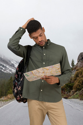 A man standing on the side of a road looking at a map