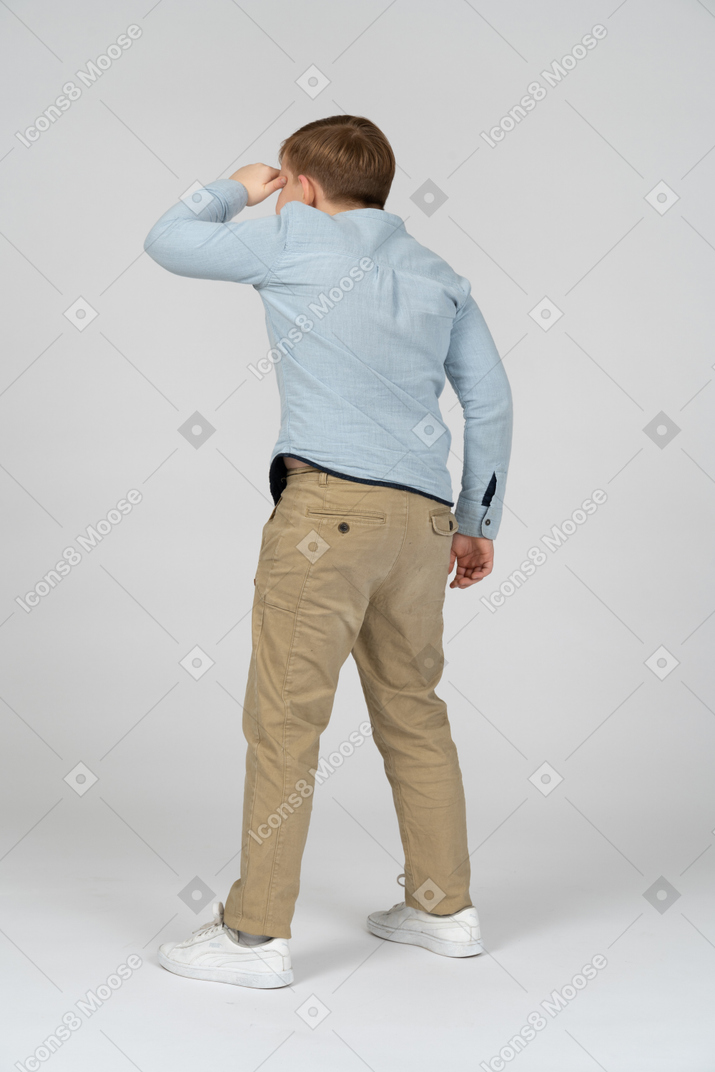 Boy looking at something with his hand above his eyes