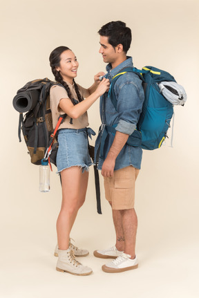 Laughing young interracial couple standing near each other with backpacks