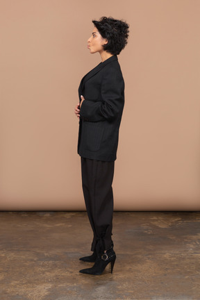 Vista laterale di una donna d'affari in un abito nero che mette le mani sullo stomaco e imbronciato