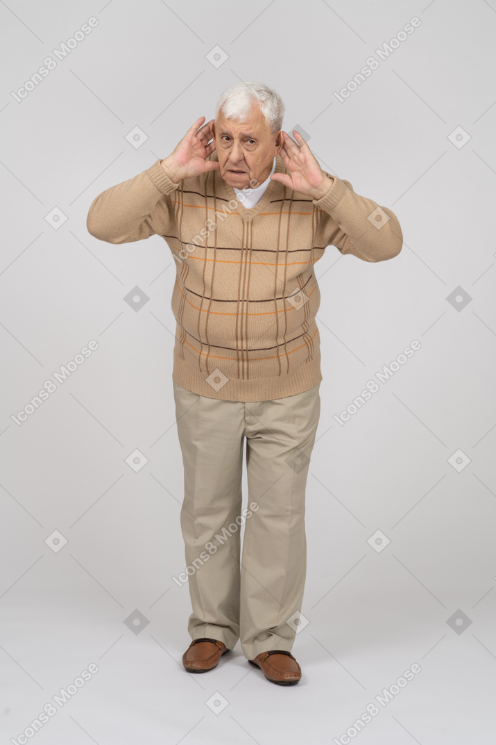 一位身着休闲服的老人的正面图握着靠近耳朵的手