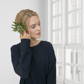 A woman holding a plant up to her ear