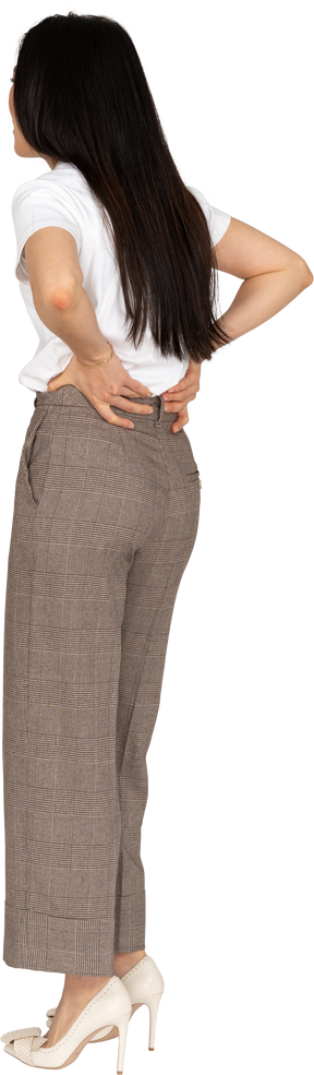 Vista posteriore di tre quarti di una giovane donna in calzoni e maglietta che le toccano la schiena