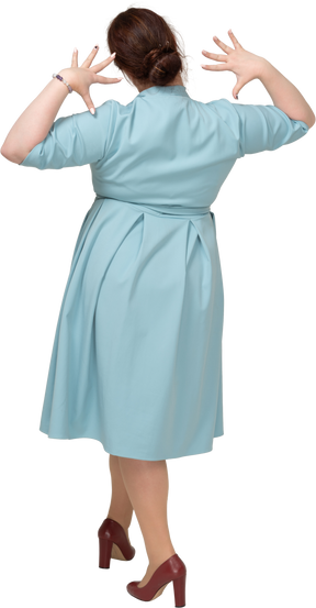 Вид сзади женщины в синем платье позирует