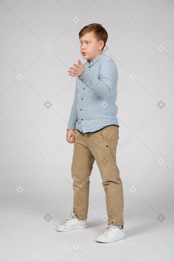 Niño de pie con una camisa azul hablando y gesticulando
