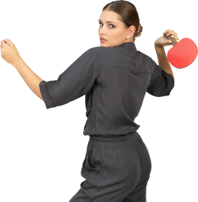 卓球をしているジャンプスーツの若い女性の4分の3の背面図
