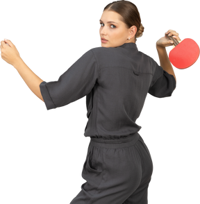 Three-quarter back view of young woman in a jumpsuit playing table tennis