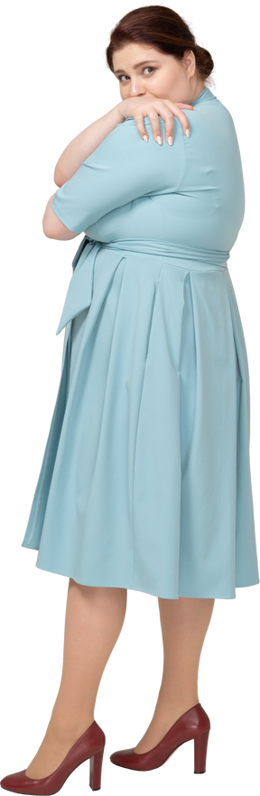 Side view of a woman in blue dress hugging herself