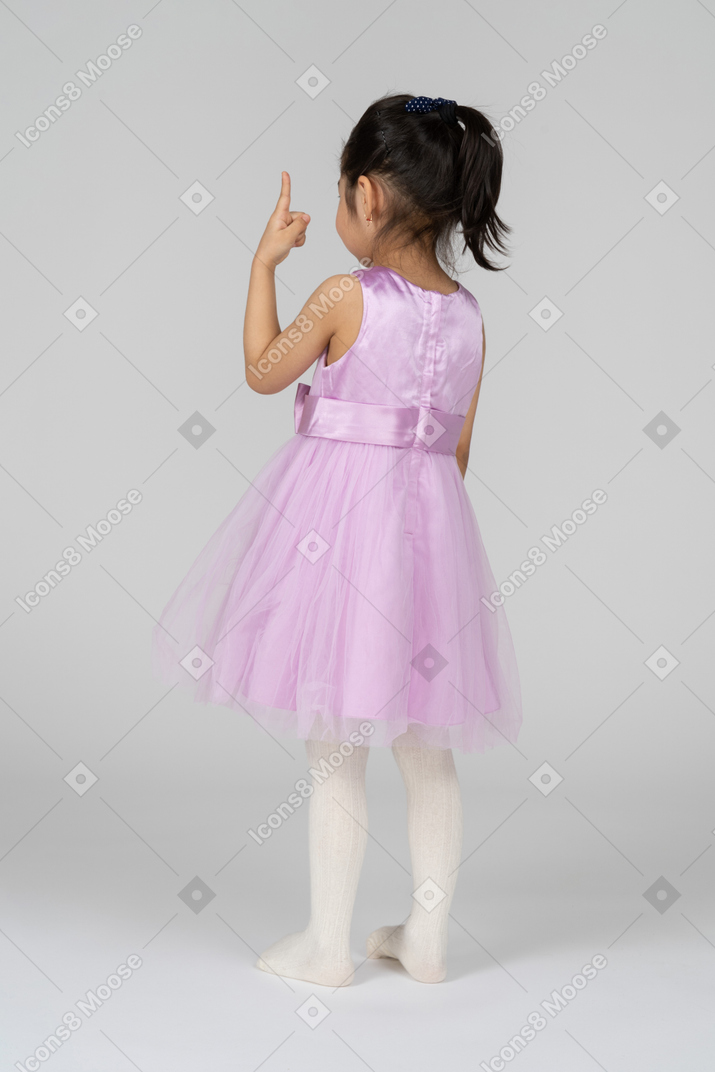 Three-quarter back view of a little girl pointing upwards