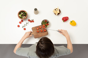 Une jeune femme ajoutant des tomates dans le bol