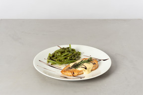 Piece of fish with white sauce and string beans