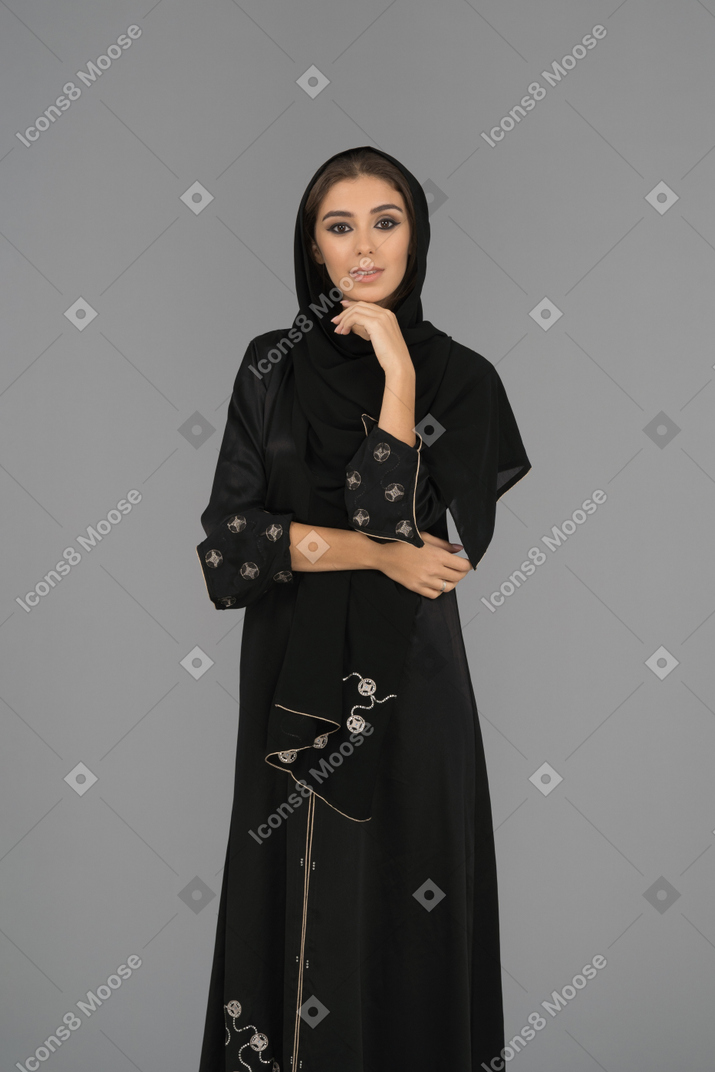 A smiling muslim woman pointing upwards