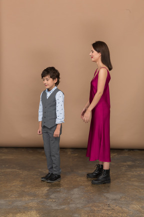 Femme en robe rouge et petit garçon debout de profil