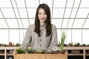 A woman standing behind a wooden planter filled with succulents