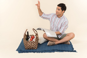Кавказский парень сидит на одеяле и держит журнал