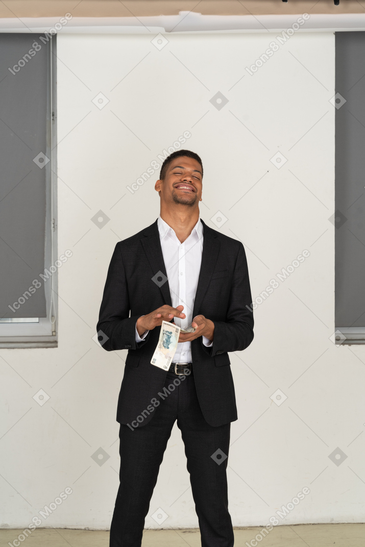 Vorderansicht eines jungen mannes im schwarzen anzug, der geld verschwendet