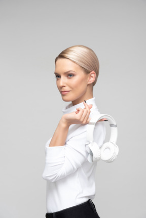 Jovem mulher segurando fones de ouvido na mão