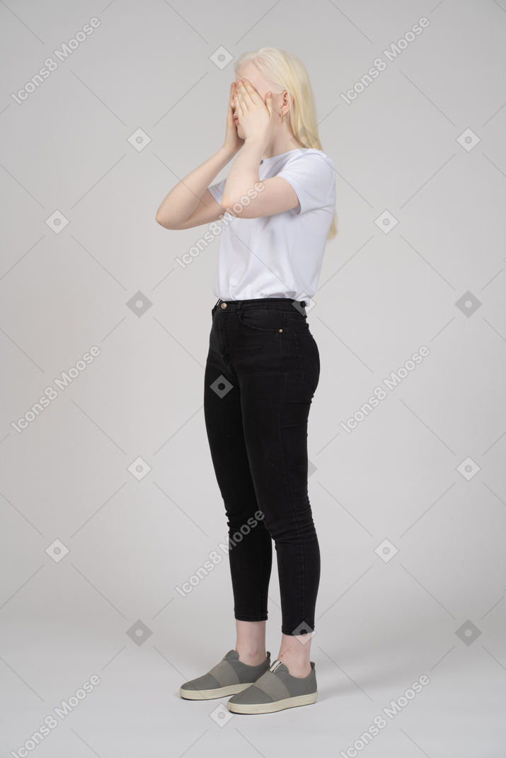 Woman in casual clothes covering her face