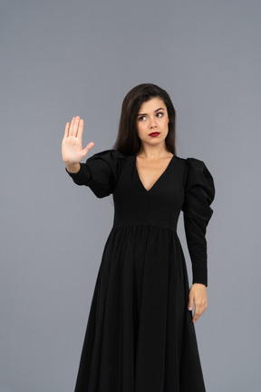 Vue de face d'une jeune femme vêtue d'une robe noire levant la main