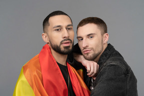 Nahaufnahme eines jungen mannes, der sich an einen anderen mann mit lgbt-flagge lehnt