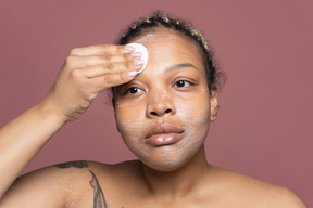 African-american woman cleansing face with a cotton pad