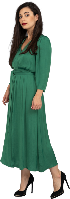 Вид в три четверти молодой леди в зеленом платье, смотрящей в камеру