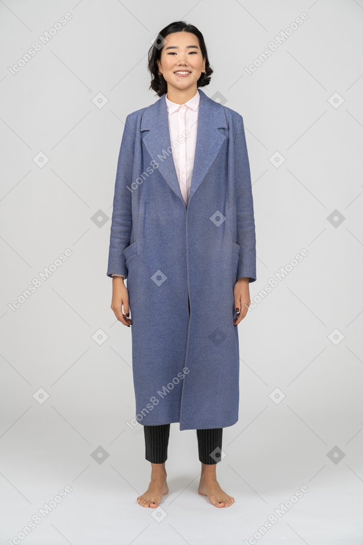 Cheeful woman in coat standing with arms at sides