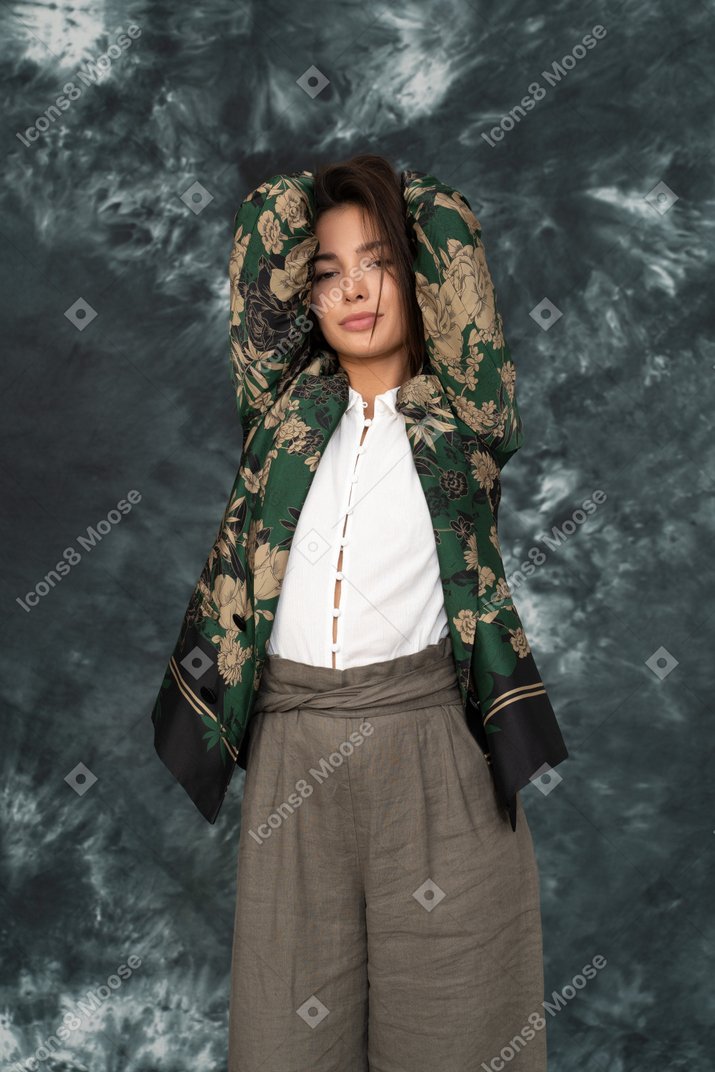 Female model in silk flower-printed jacket holding hands behind head