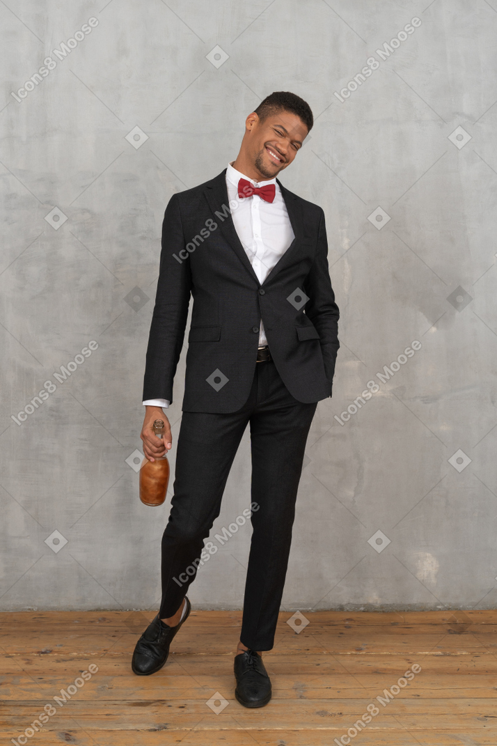 Hombre alegre caminando con una botella de licor en la mano