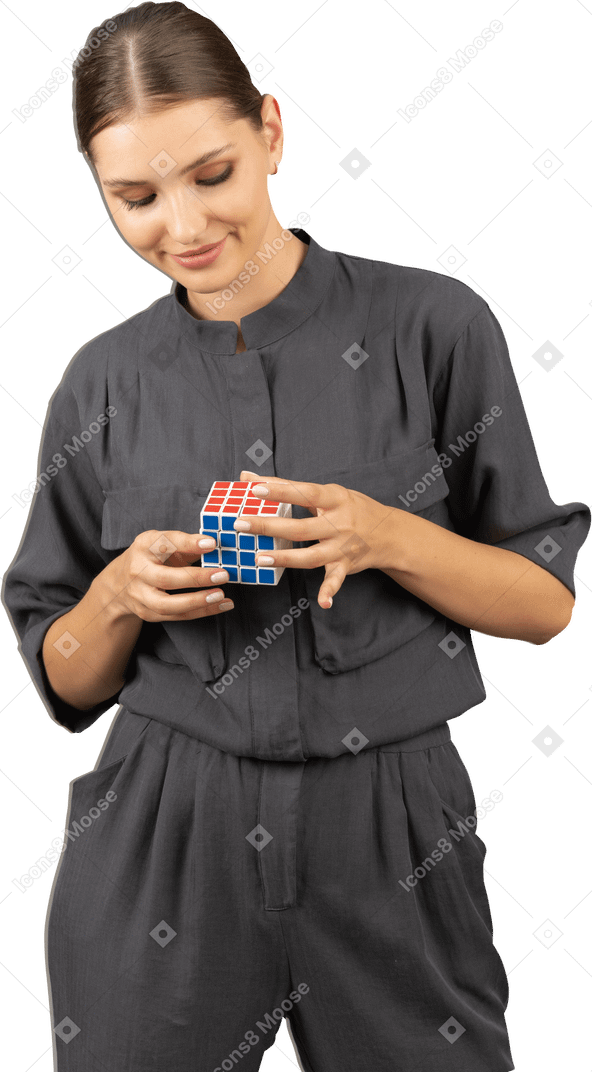 Front view of a smiling young woman in a jumpsuit holding the rubik's cube