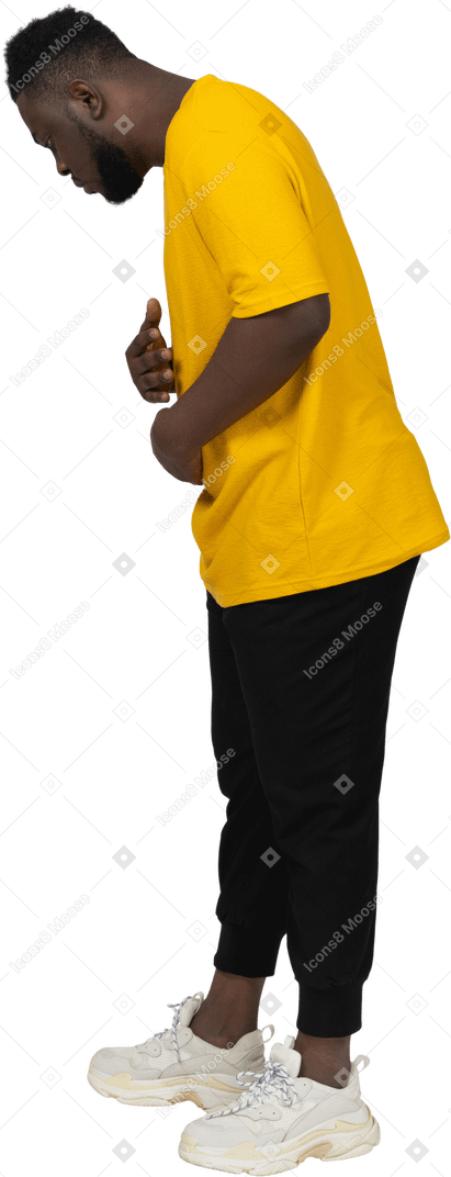 Seitenansicht eines jungen dunkelhäutigen mannes in gelbem t-shirt, der den bauch berührt und nach unten schaut
