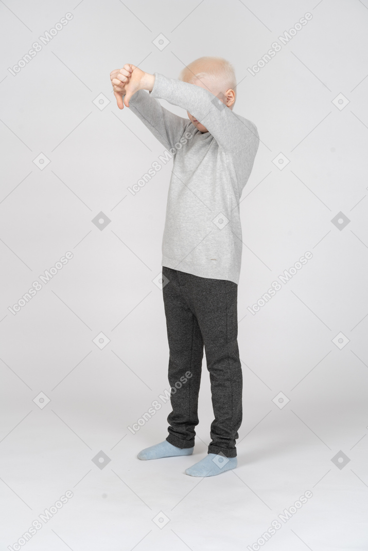 Little boy showing a gesture with thumbs down