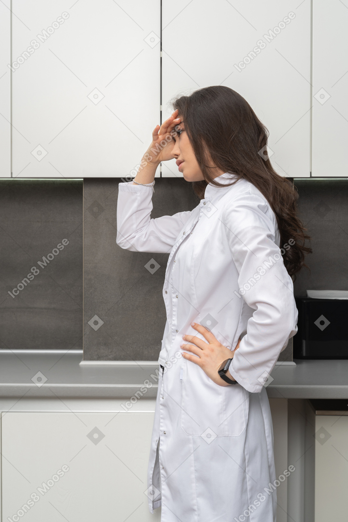 Side view of a displeased female doctor touching her forehead