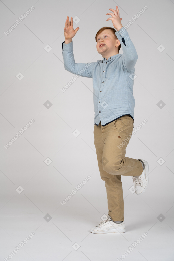 Boy standing on one leg with raised arms