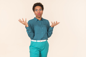 Black woman with a short haircut, wearing all blue, standing against a plain pastel background, looking emotional