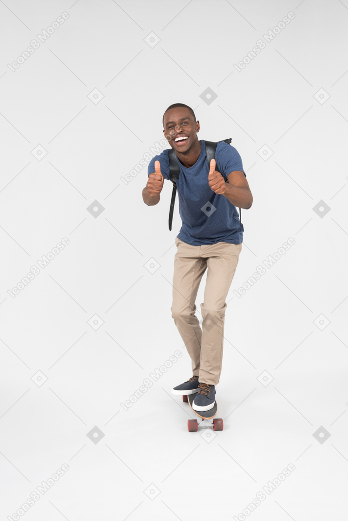 Male black tourist standing on skateboard and showing thumbs up