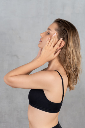 Side view of a young woman touching her face