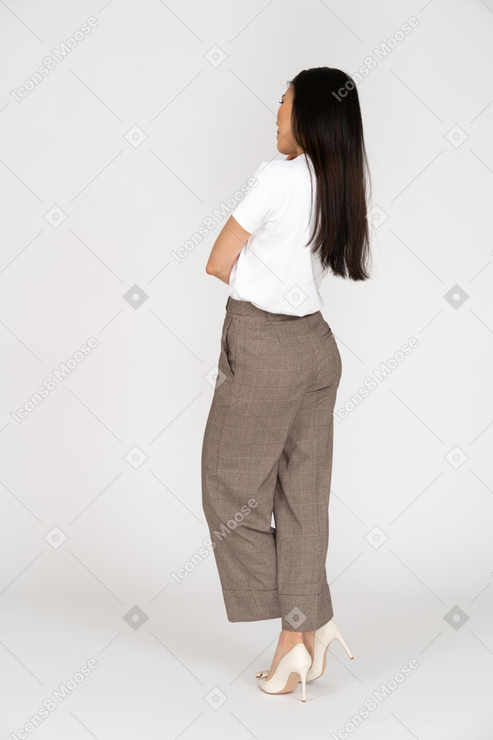 Vista posteriore di tre quarti di una giovane donna premurosa in calzoni che incrociano le gambe