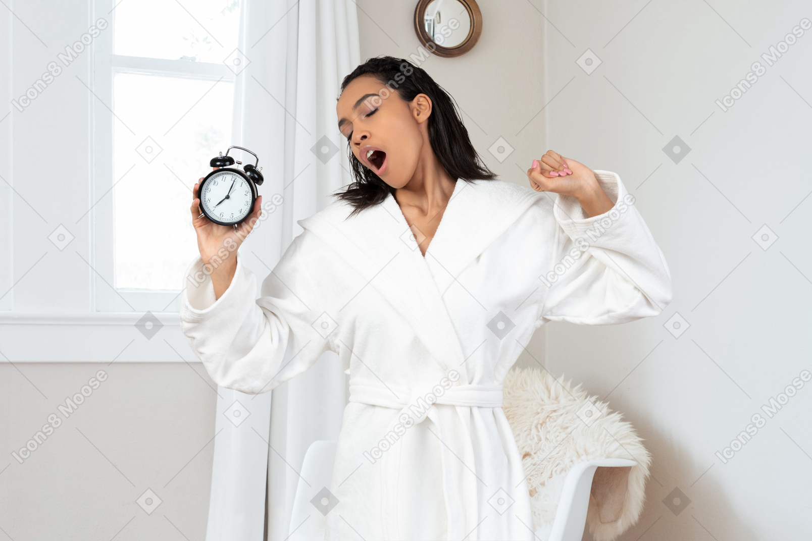 A woman in a robe holding an alarm clock