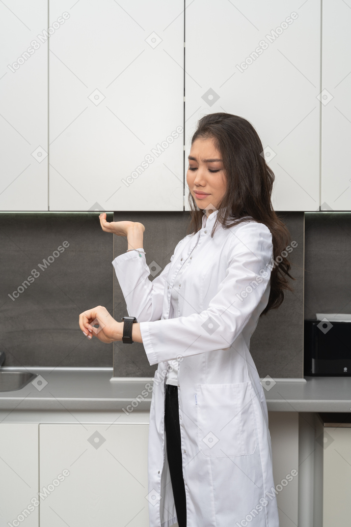 困惑的女护士，看着她的手表，举起一只手