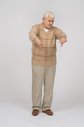 Vue de face d'un vieil homme en vêtements décontractés montrant les pouces vers le bas