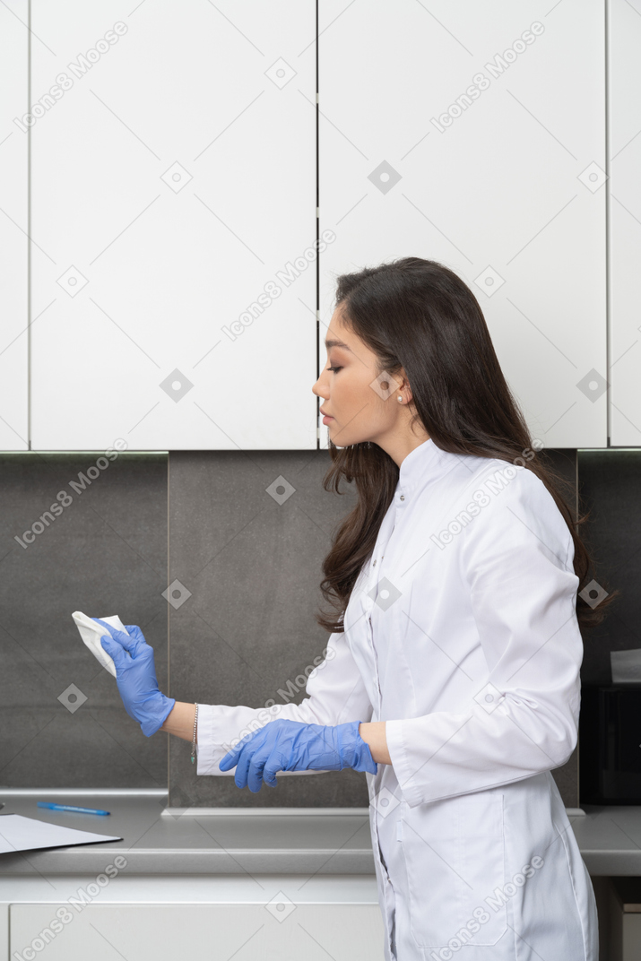 그녀의 의료 캐비닛을 청소하는 여성 의사의 측면보기