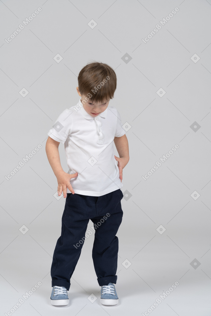 Front view of little kid standing and looking down